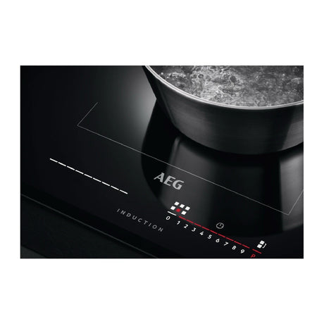 AEG IKE85651 80cm Multibridge Induction Hob from HomeWise Appliances stock photo showing active touch controls illuminated whilst a pan has been detected with Maxisense.